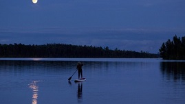  A person on a paddle board on a lake at dusk 